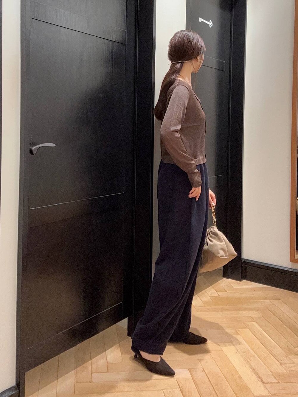 ブルー系のスウェットパンツ、ブラウン系のパンプス、ベージュ系のショルダーバッグを着用したレディースの夏コーディネートの2枚目の写真