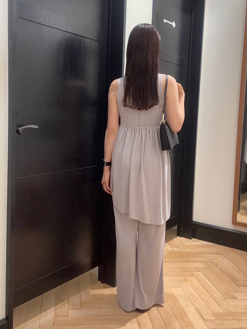 ブラウン系のサンダル、グレー系のセットアップ、ブラック系のショルダーバッグを着用したレディースの夏コーディネートの3枚目の写真