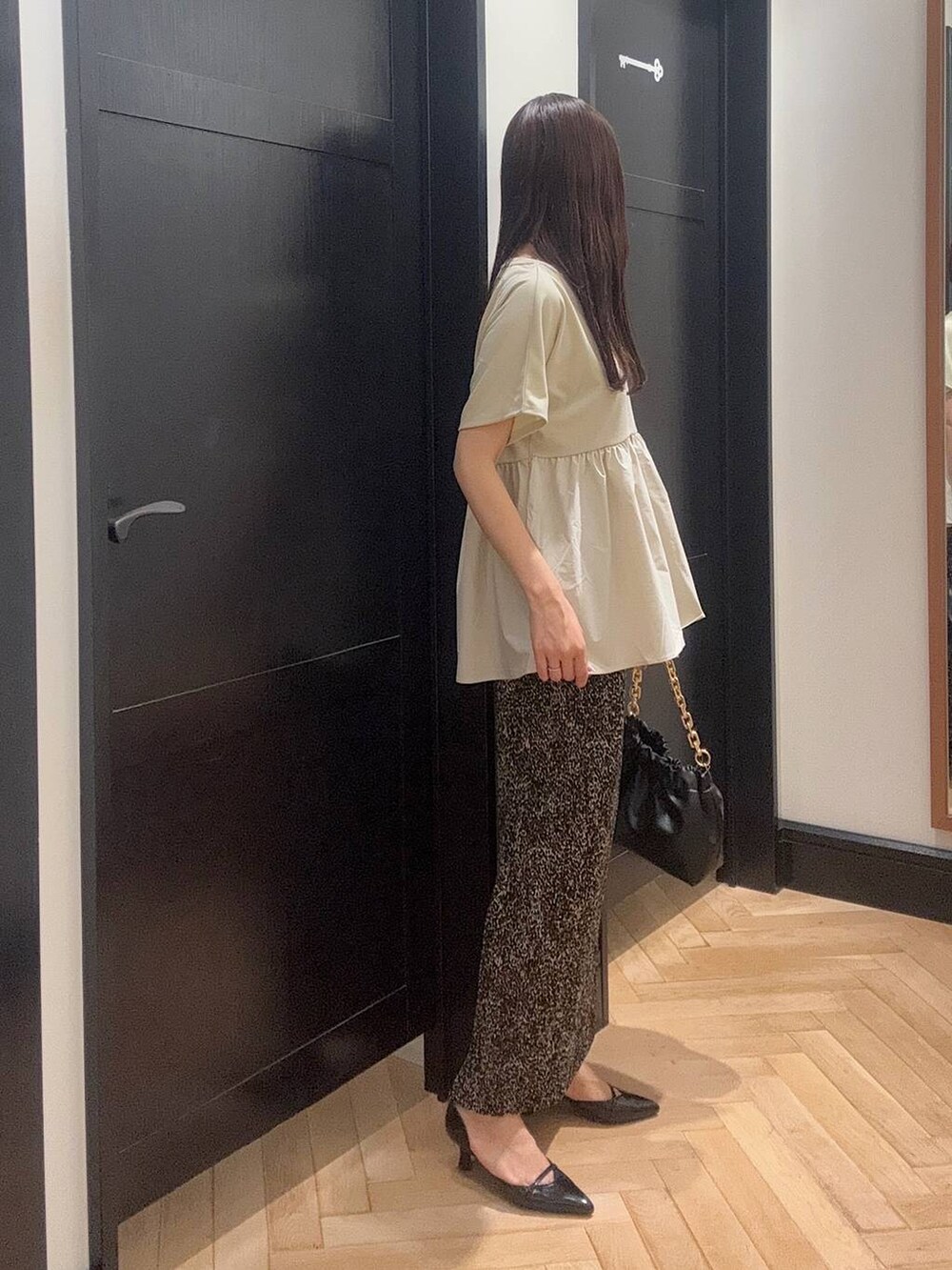 ブラウン系のスカート、ブラック系のパンプス、ブラック系のショルダーバッグを着用したレディースの夏コーディネートの2枚目の写真