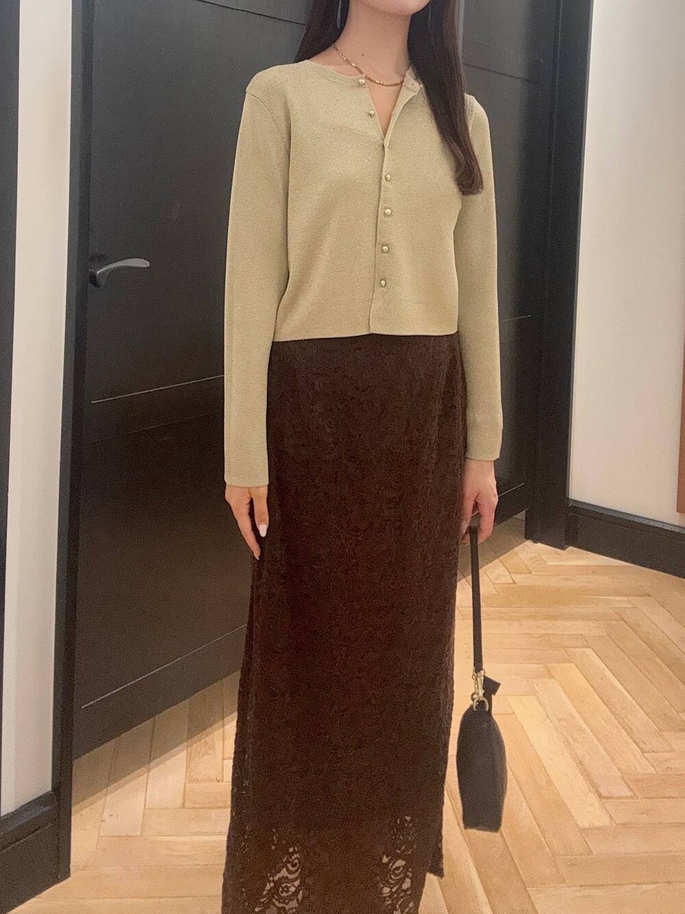 ゴールド系のカーディガン/ボレロ、ブラウン系のスカート、ブラック系のショルダーバッグを着用したレディースの夏コーディネートの4枚目の写真