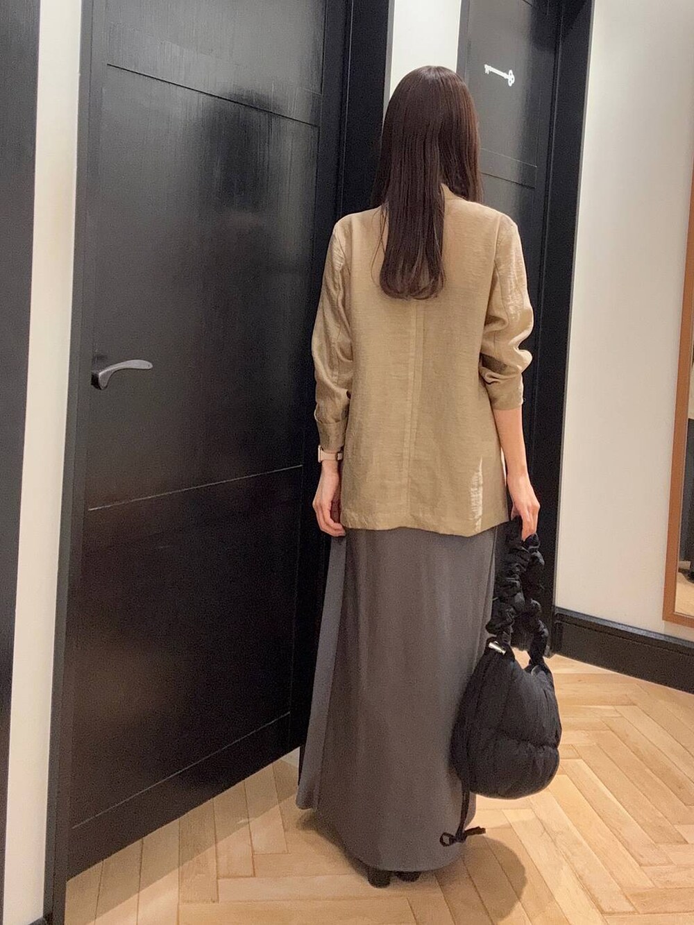 ブラック系のパンプス、ベージュ系のテーラードジャケット、グレー系のスカートを着用したレディースの夏コーディネートの3枚目の写真