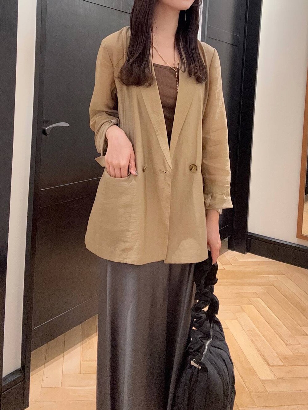 ブラック系のパンプス、ベージュ系のテーラードジャケット、グレー系のスカートを着用したレディースの夏コーディネートの4枚目の写真