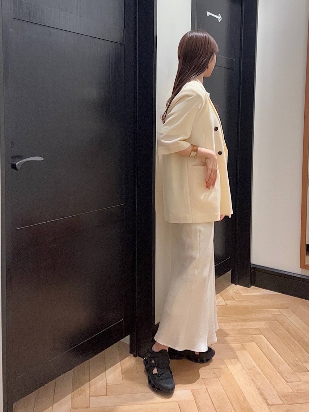 ホワイト系のスカート、ホワイト系のTシャツ/カットソー、ブラック系のスニーカーを着用したレディースの夏コーディネートの2枚目の写真