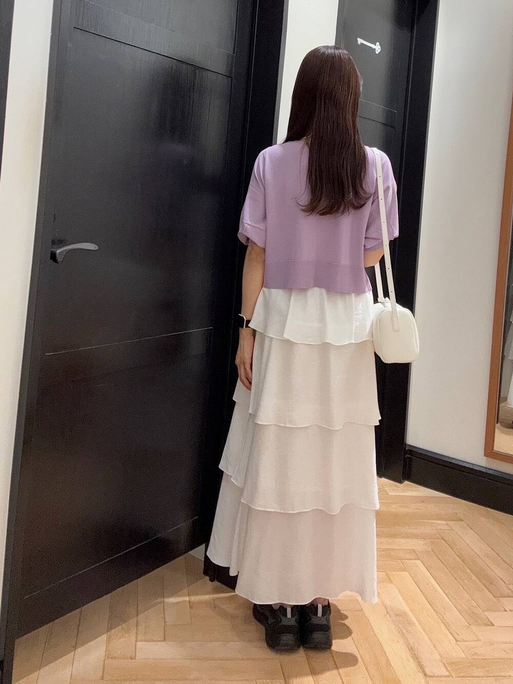 ホワイト系のハンドバッグ、ブラック系のスニーカー、シルバー系のネックレスを着用したレディースの夏コーディネートの3枚目の写真