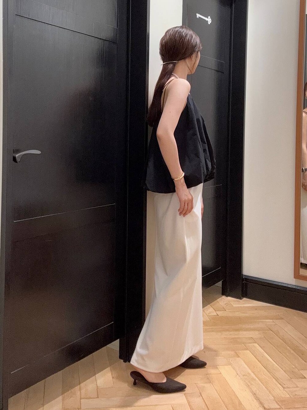 ホワイト系のセットアップ、ブラウン系のパンプス、ブラック系のショルダーバッグを着用したレディースの夏コーディネートの2枚目の写真