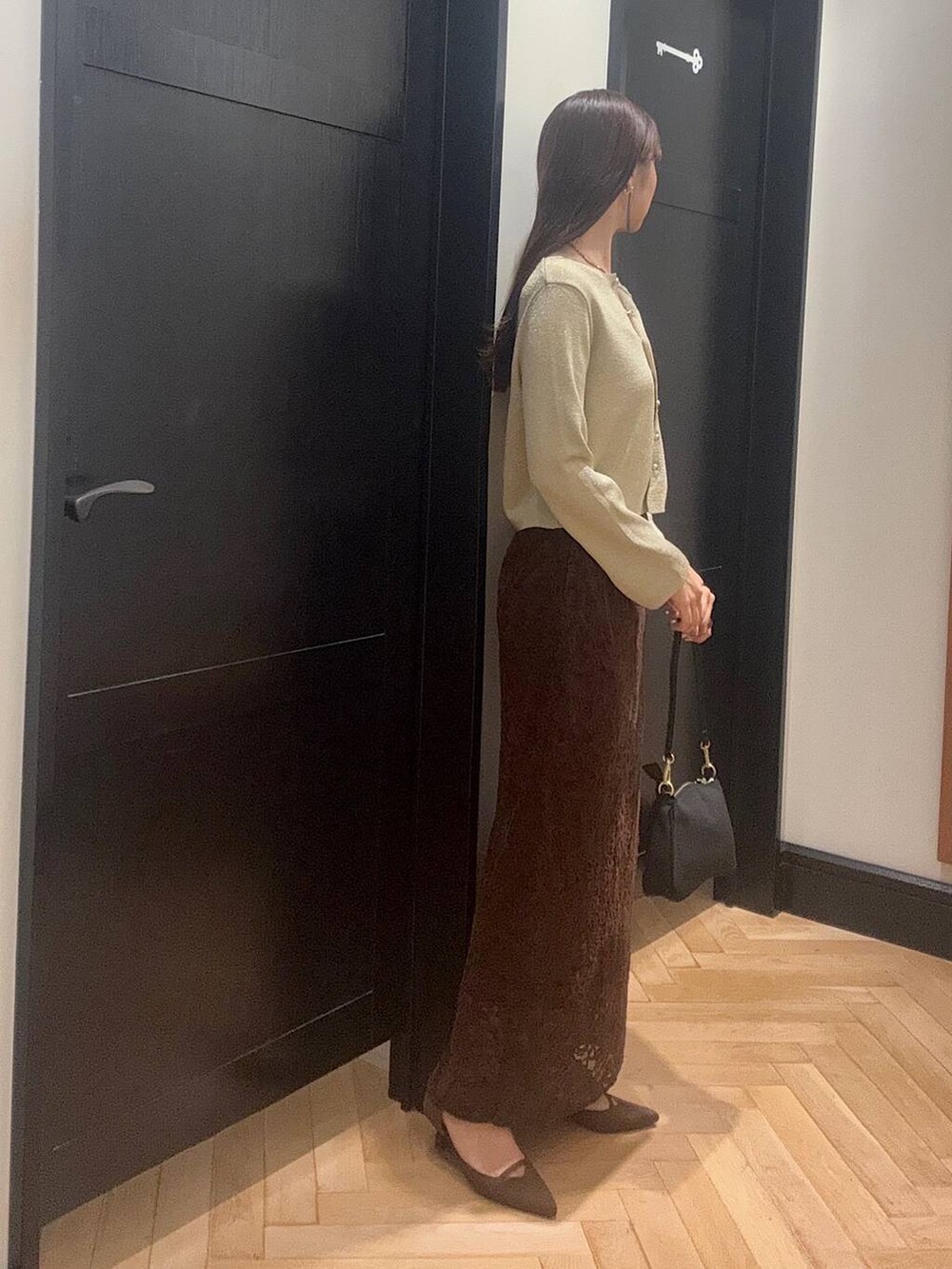 ゴールド系のカーディガン/ボレロ、ブラウン系のスカート、ブラック系のショルダーバッグを着用したレディースの夏コーディネートの2枚目の写真