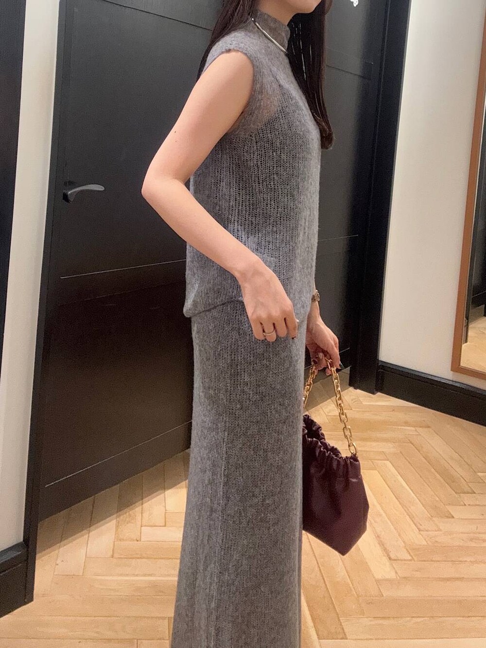 グレー系のワンピース、レッド系のショルダーバッグ、ブラック系のブーツを着用したレディースの秋コーディネートの4枚目の写真