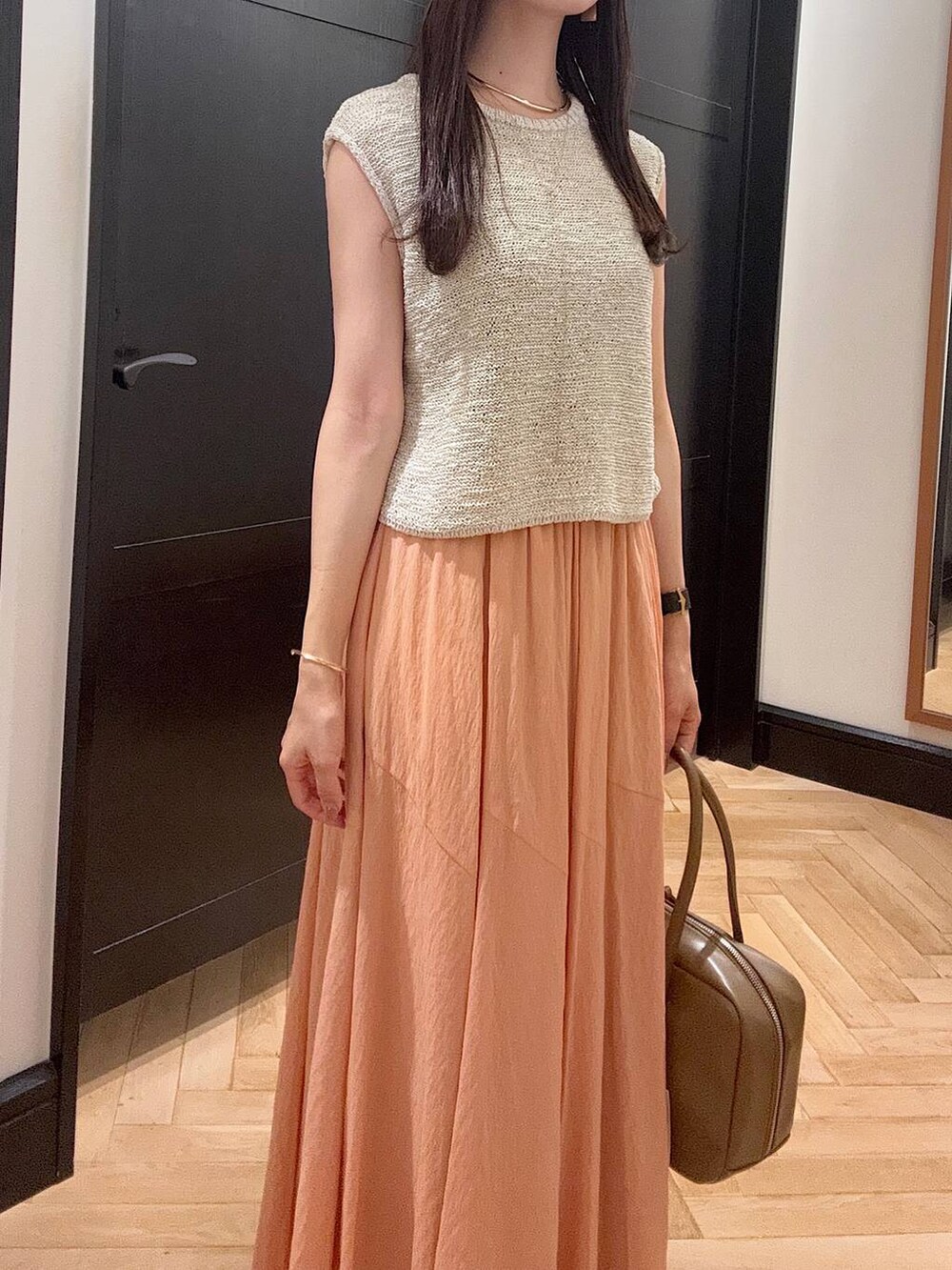 ブラウン系のボストンバッグ、シルバー系のパンプス、ホワイト系のニット/セーターを着用したレディースの夏コーディネートの4枚目の写真