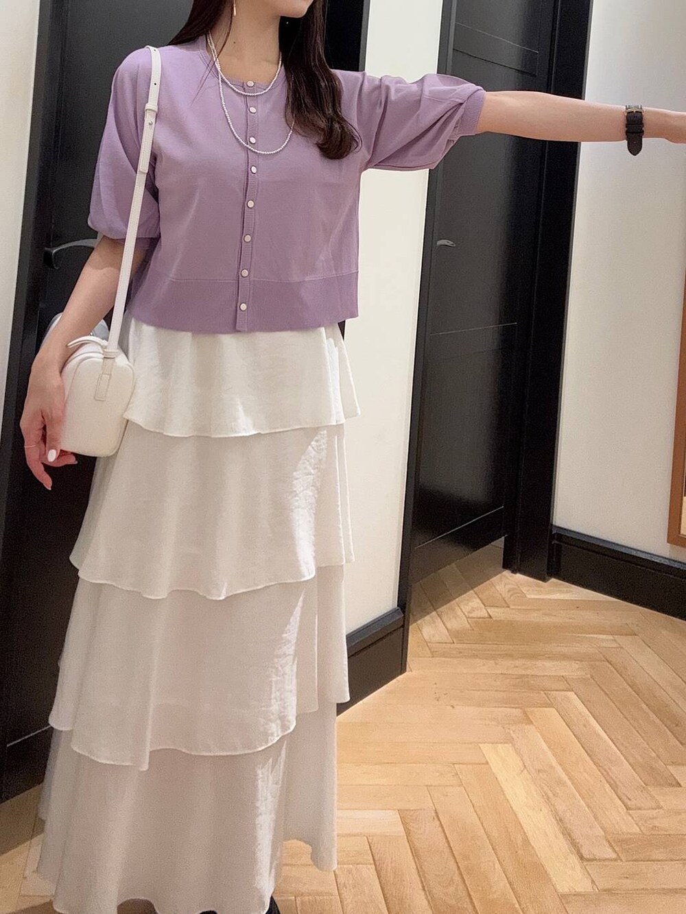 ホワイト系のハンドバッグ、ブラック系のスニーカー、シルバー系のネックレスを着用したレディースの夏コーディネートの4枚目の写真