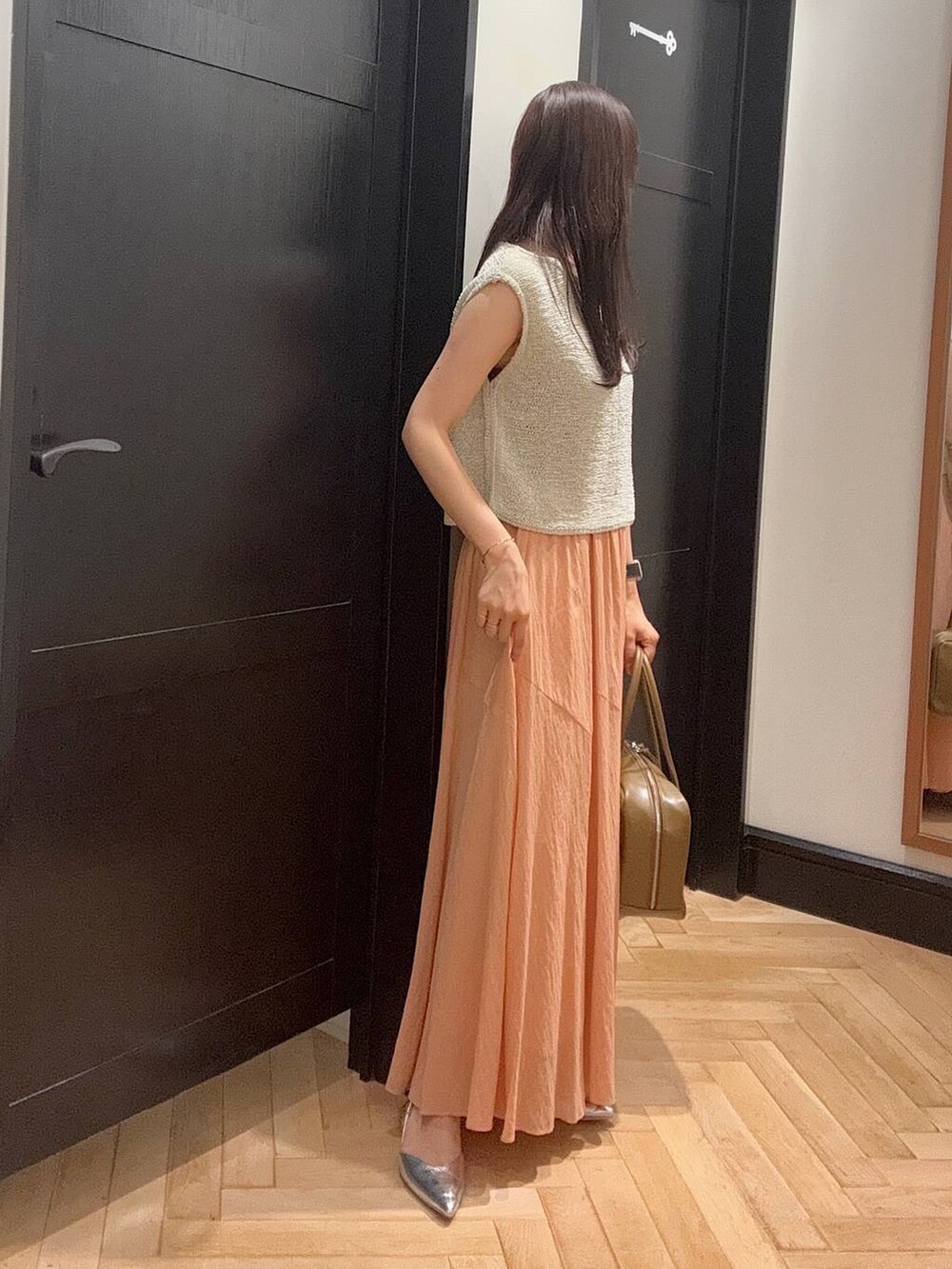 ブラウン系のボストンバッグ、シルバー系のパンプス、ホワイト系のニット/セーターを着用したレディースの夏コーディネートの2枚目の写真