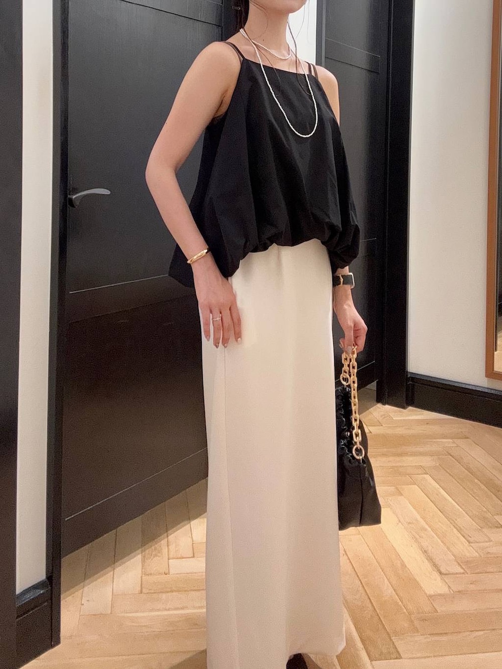 ホワイト系のセットアップ、ブラウン系のパンプス、ブラック系のショルダーバッグを着用したレディースの夏コーディネートの3枚目の写真