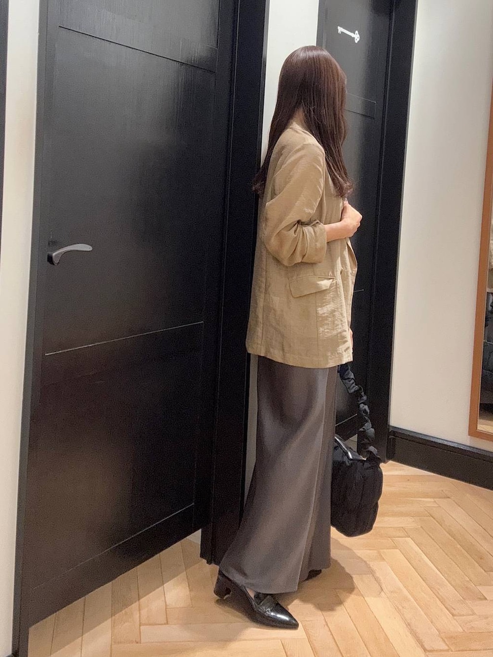 ブラック系のパンプス、ベージュ系のテーラードジャケット、グレー系のスカートを着用したレディースの夏コーディネートの2枚目の写真