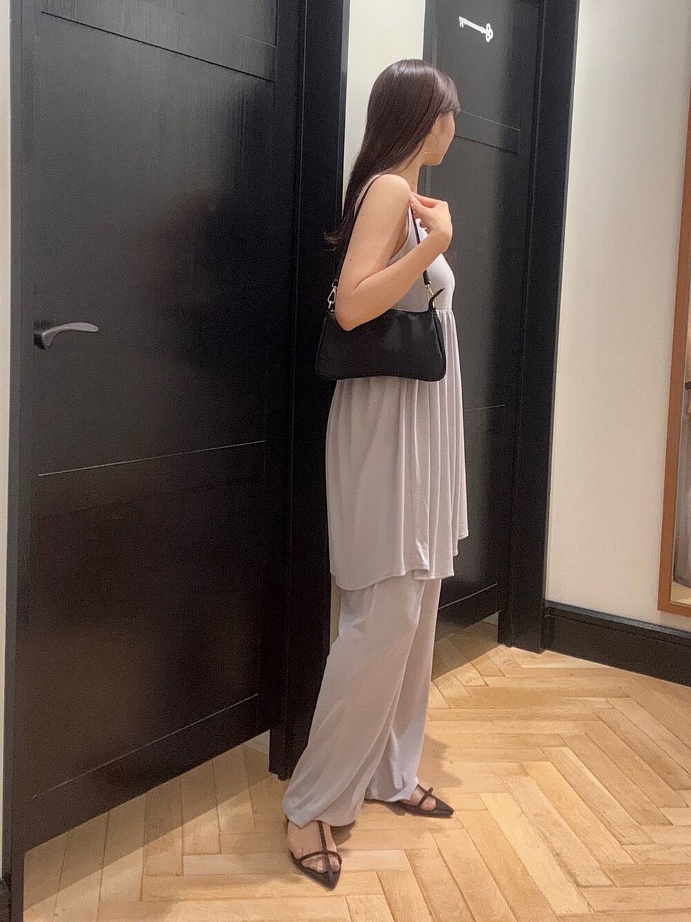 ブラウン系のサンダル、グレー系のセットアップ、ブラック系のショルダーバッグを着用したレディースの夏コーディネートの2枚目の写真