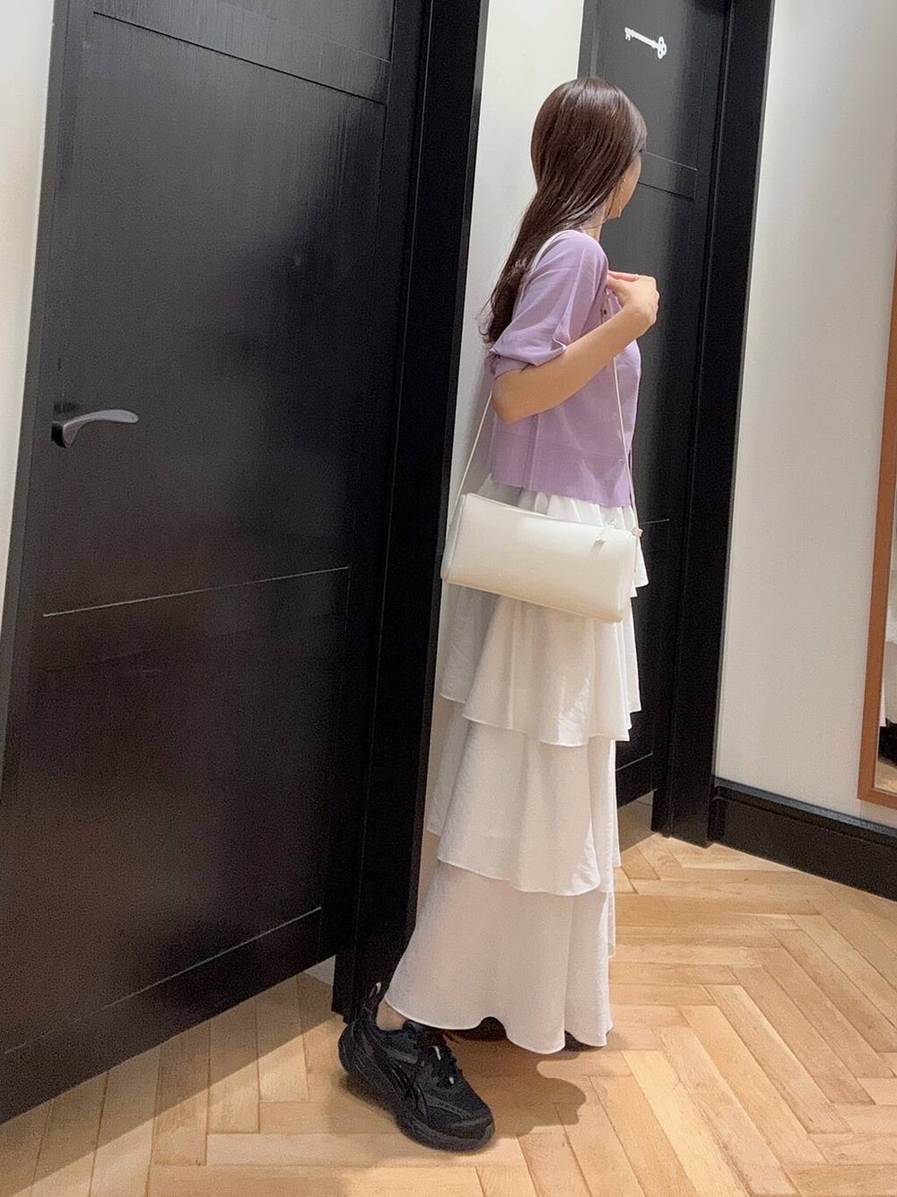 ホワイト系のハンドバッグ、ブラック系のスニーカー、シルバー系のネックレスを着用したレディースの夏コーディネートの2枚目の写真