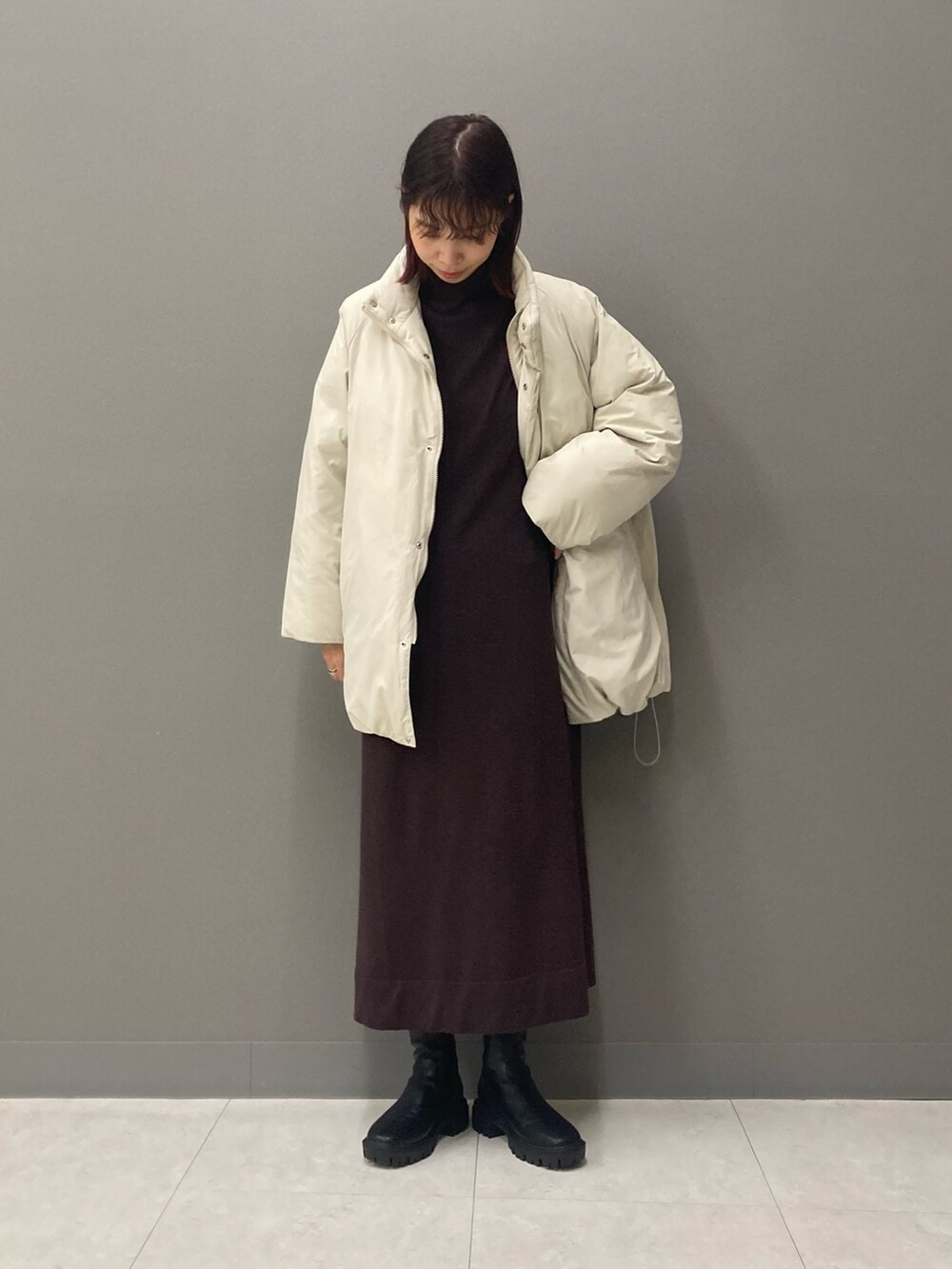 ブラウン系のワンピース、ブラック系のブーツ、ホワイト系のブルゾンを着用したレディースの冬コーディネートの5枚目の写真