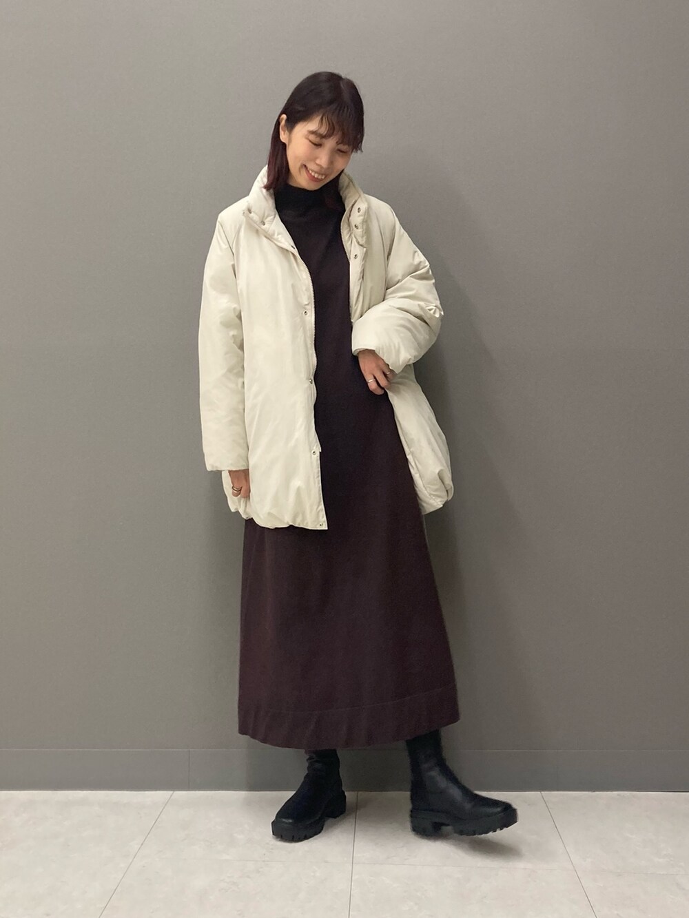 ブラウン系のワンピース、ブラック系のブーツ、ホワイト系のブルゾンを着用したレディースの冬コーディネートの4枚目の写真