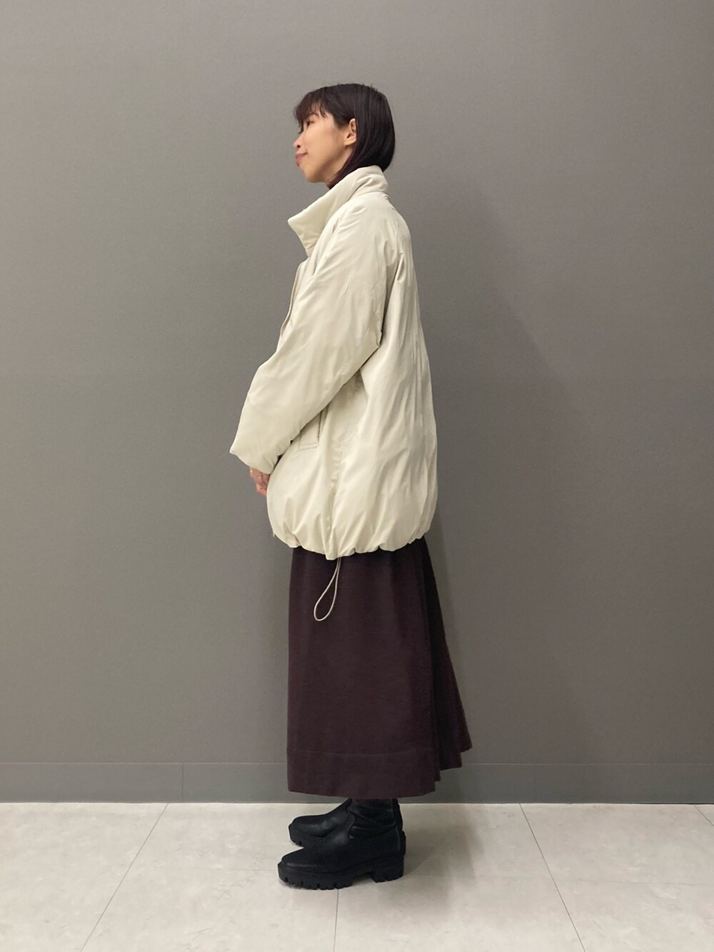 ブラウン系のワンピース、ブラック系のブーツ、ホワイト系のブルゾンを着用したレディースの冬コーディネートの6枚目の写真