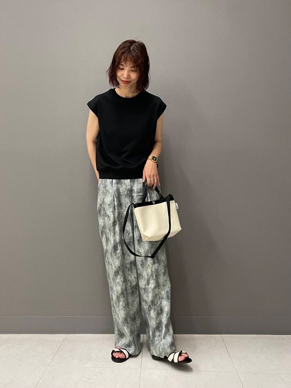 ホワイト系のサンダル、ブラック系のTシャツ/カットソー、ホワイト系のショルダーバッグを着用したレディースの夏コーディネートの2枚目の写真