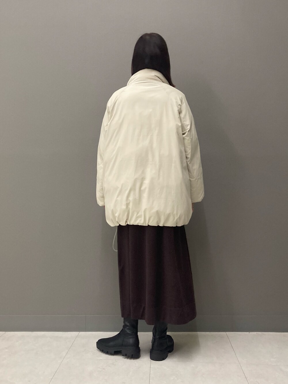 ブラウン系のワンピース、ブラック系のブーツ、ホワイト系のブルゾンを着用したレディースの冬コーディネートの7枚目の写真