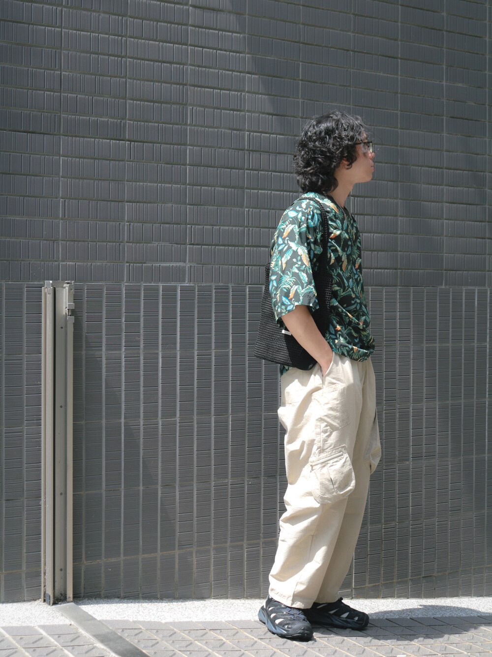 グリーン系のTシャツ/カットソー、ベージュ系のチノパンツ、ブラック系のサンダルを着用したメンズの夏コーディネートの2枚目の写真