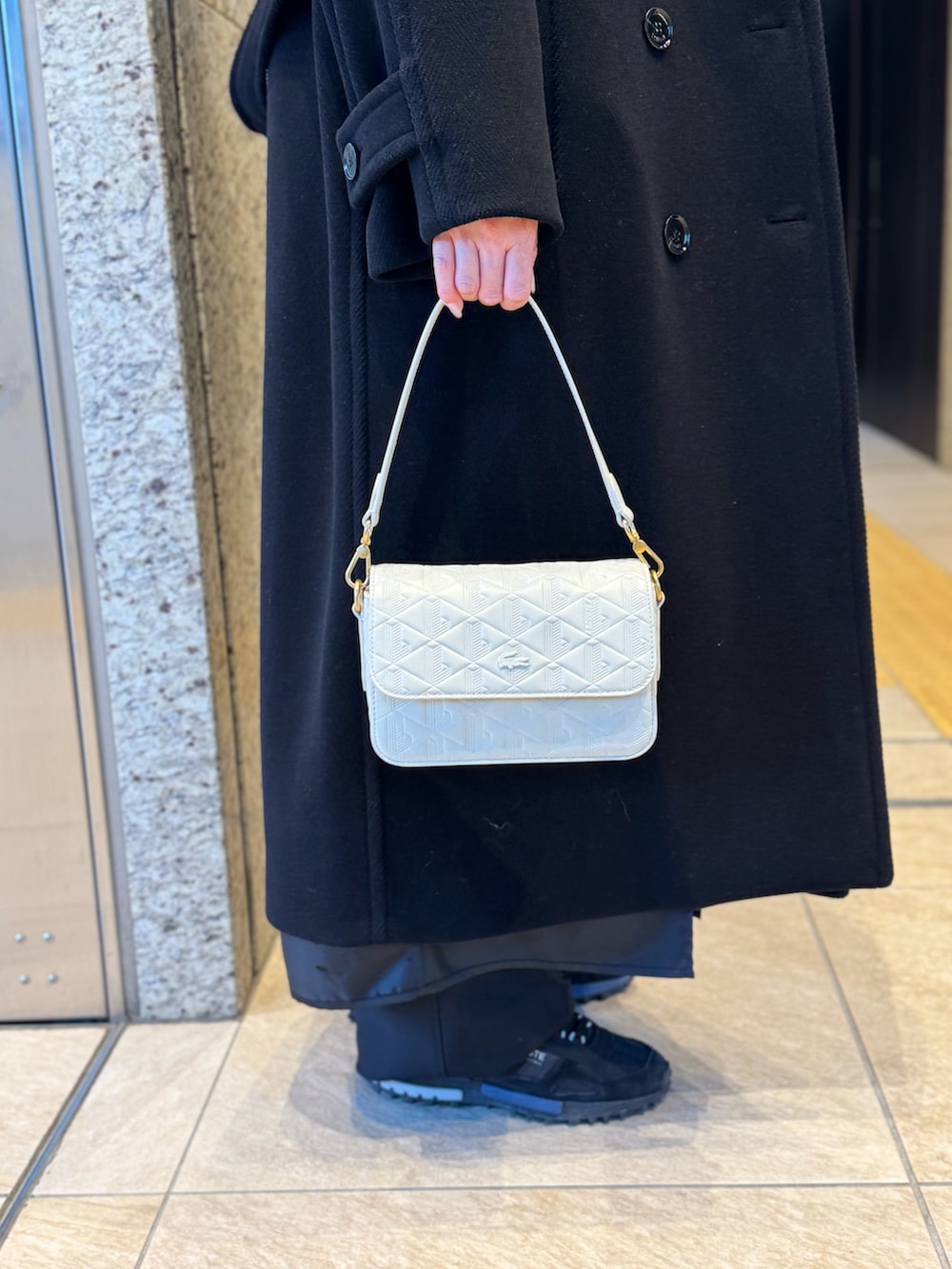 ブラック系のジャケット/アウター、ホワイト系のメッセンジャーバッグ、ブラック系のスニーカーを着用したレディースの冬コーディネートの5枚目の写真