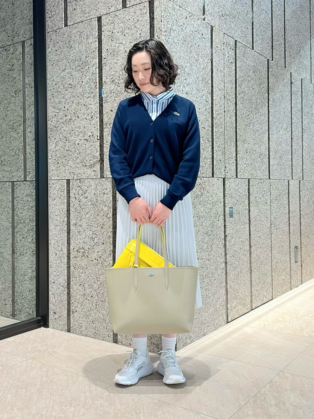 ホワイト系のスカート、ホワイト系のスニーカー、ブルー系のニット/セーターを着用したレディースの春コーディネートの2枚目の写真