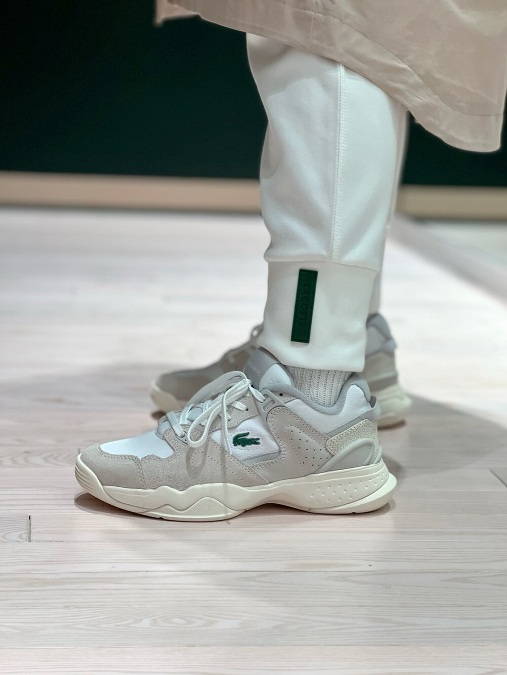 ホワイト系のスニーカー、ホワイト系のスウェットパンツ、ベージュ系のステンカラーコートを着用したレディースの春コーディネートの6枚目の写真