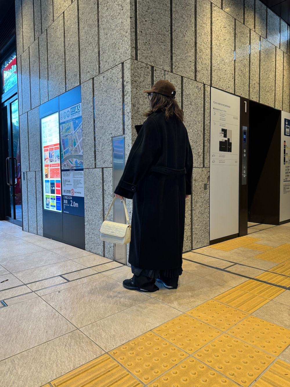 ブラック系のジャケット/アウター、ホワイト系のメッセンジャーバッグ、ブラック系のスニーカーを着用したレディースの冬コーディネートの3枚目の写真