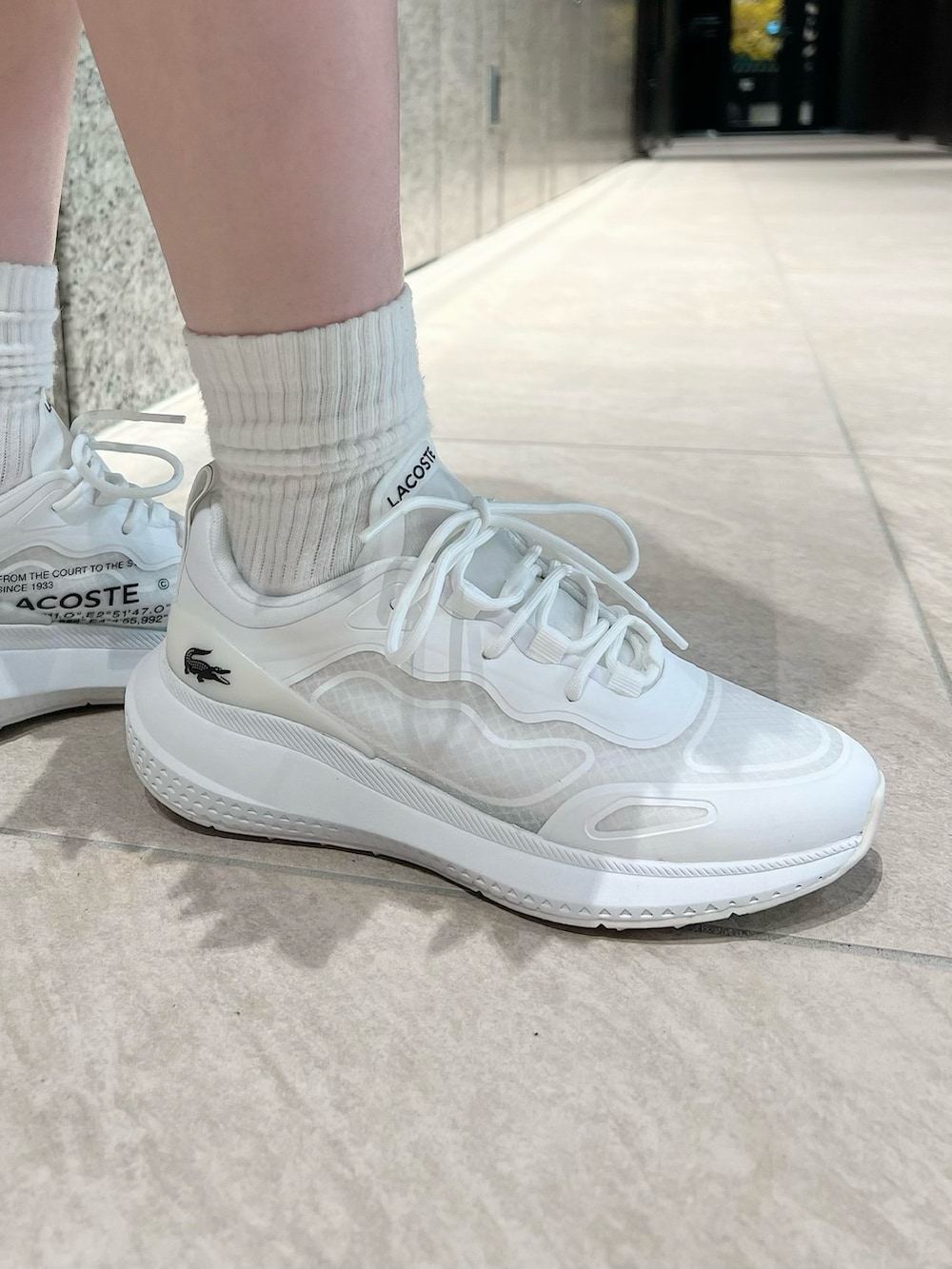 ホワイト系のスカート、ホワイト系のスニーカー、ブルー系のニット/セーターを着用したレディースの春コーディネートの6枚目の写真