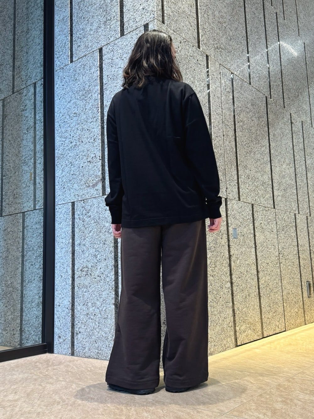 ブラック系のTシャツ/カットソー、ブラウン系のスウェットパンツ、ブラック系のスニーカーを着用したレディースの秋コーディネートの3枚目の写真