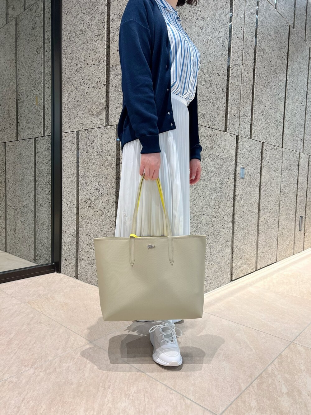 ホワイト系のスカート、ホワイト系のスニーカー、ブルー系のニット/セーターを着用したレディースの春コーディネートの5枚目の写真