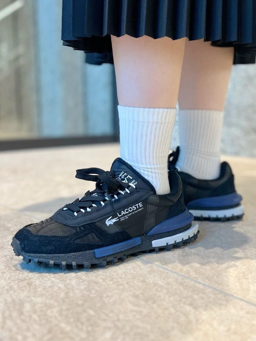 ブラック系のブルゾン、ホワイト系のポロシャツ、シルバー系のショルダーバッグを着用したレディースの秋コーディネートの7枚目の写真