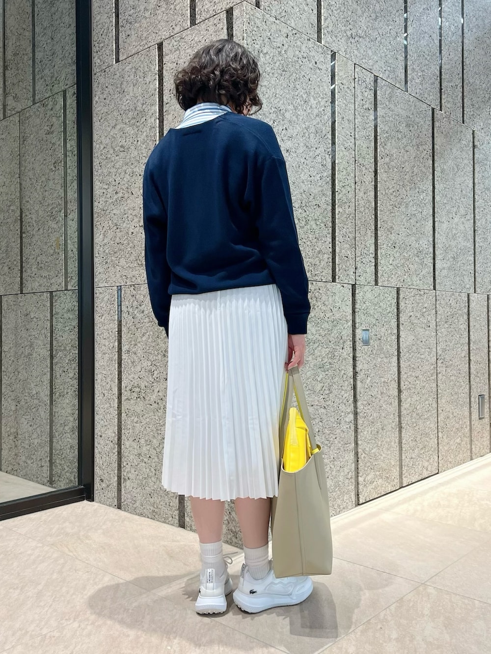 ホワイト系のスカート、ホワイト系のスニーカー、ブルー系のニット/セーターを着用したレディースの春コーディネートの3枚目の写真