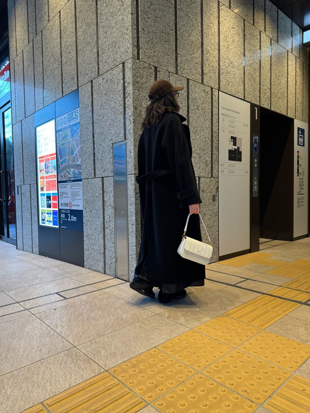 ブラック系のジャケット/アウター、ホワイト系のメッセンジャーバッグ、ブラック系のスニーカーを着用したレディースの冬コーディネートの2枚目の写真