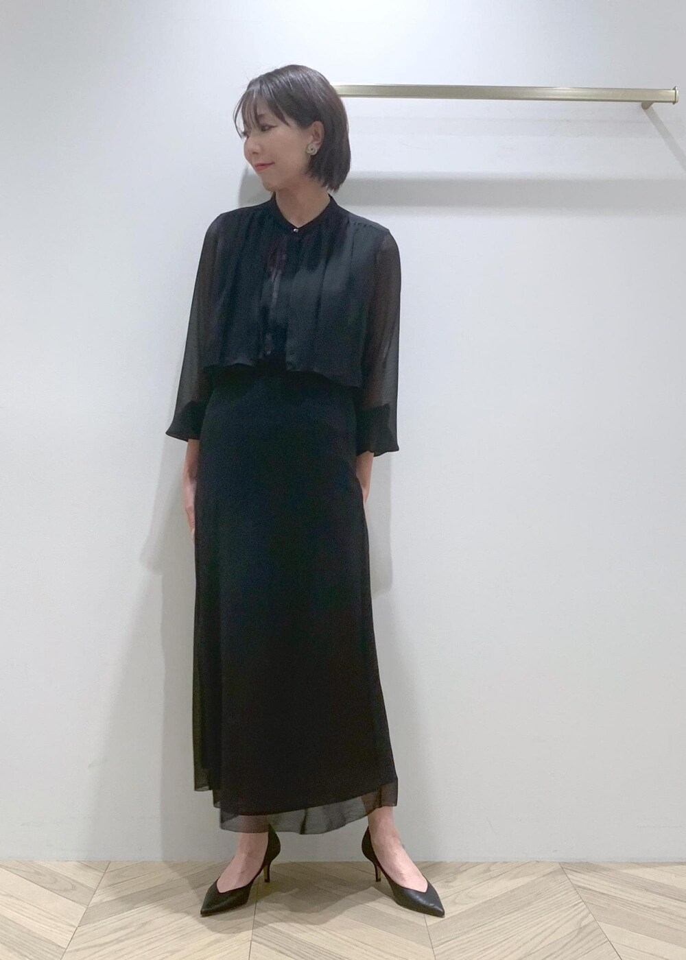 ブラック系のパンプス、ブラック系のシャツ/ブラウス、ブラック系のスカートを着用したレディースの春コーディネートの2枚目の写真