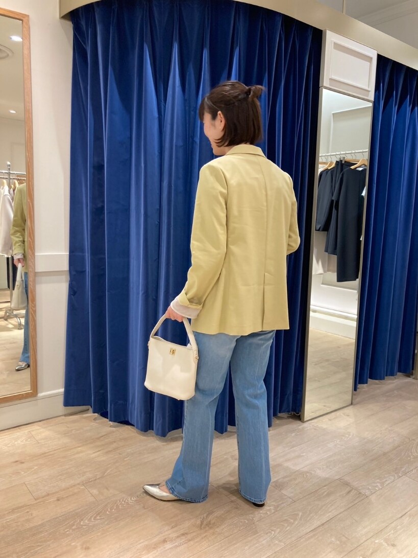 イエロー系のテーラードジャケット、ブルー系のデニムパンツ、ゴールド系のパンプスを着用したレディースの春コーディネートの3枚目の写真
