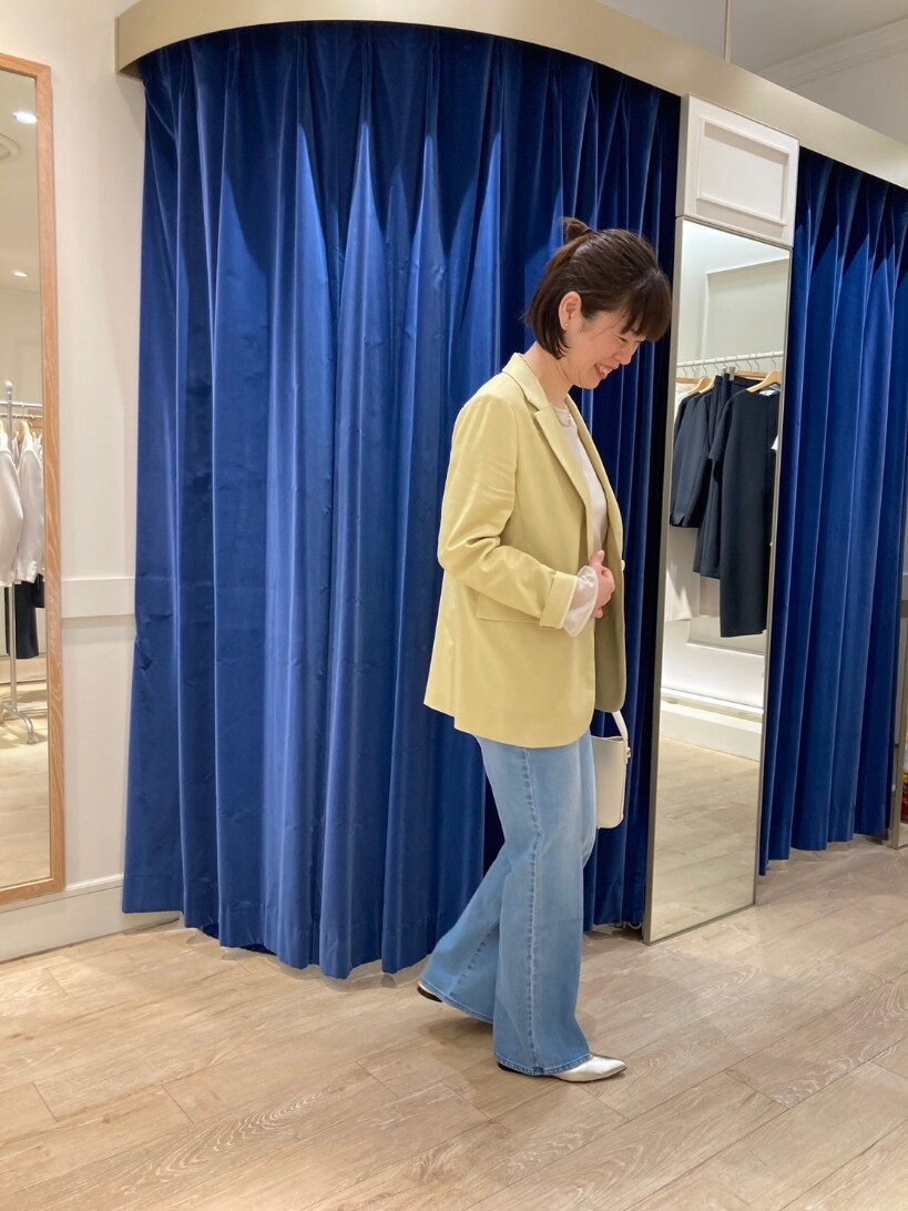イエロー系のテーラードジャケット、ブルー系のデニムパンツ、ゴールド系のパンプスを着用したレディースの春コーディネートの4枚目の写真