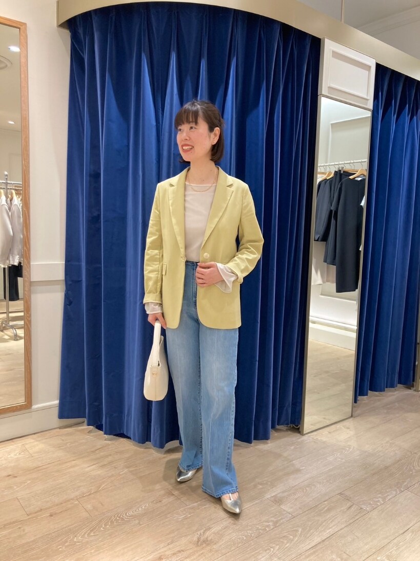 イエロー系のテーラードジャケット、ブルー系のデニムパンツ、ゴールド系のパンプスを着用したレディースの春コーディネートの6枚目の写真