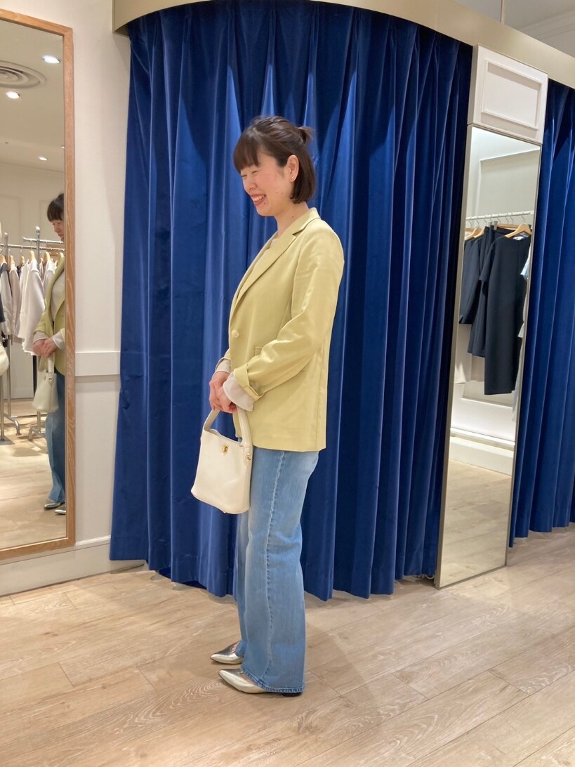 イエロー系のテーラードジャケット、ブルー系のデニムパンツ、ゴールド系のパンプスを着用したレディースの春コーディネートの2枚目の写真