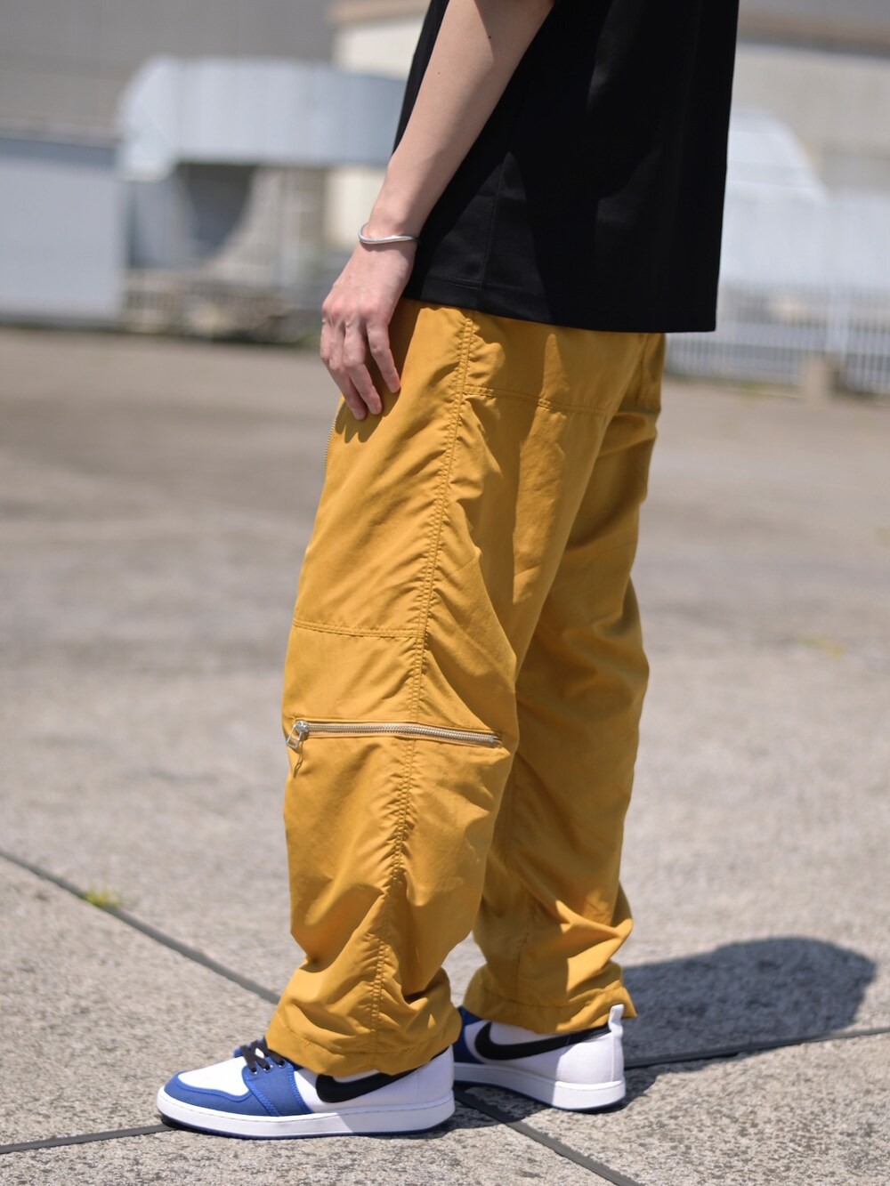 ブラック系のTシャツ/カットソー、イエロー系のカーゴパンツを着用したメンズの春コーディネートの4枚目の写真