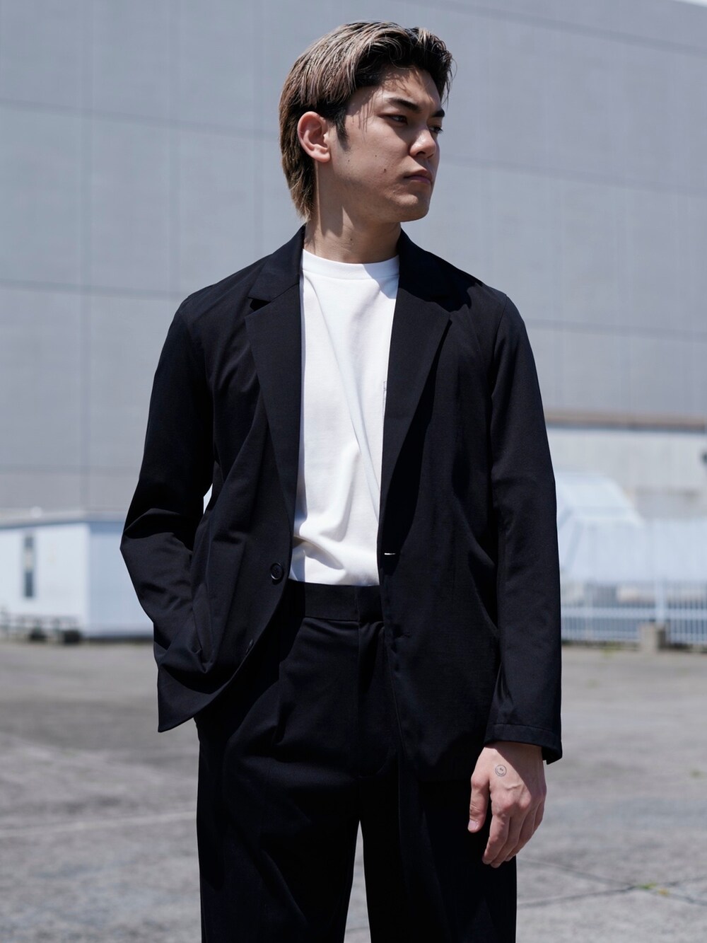 ブラック系のテーラードジャケットを着用したメンズの春コーディネートの2枚目の写真