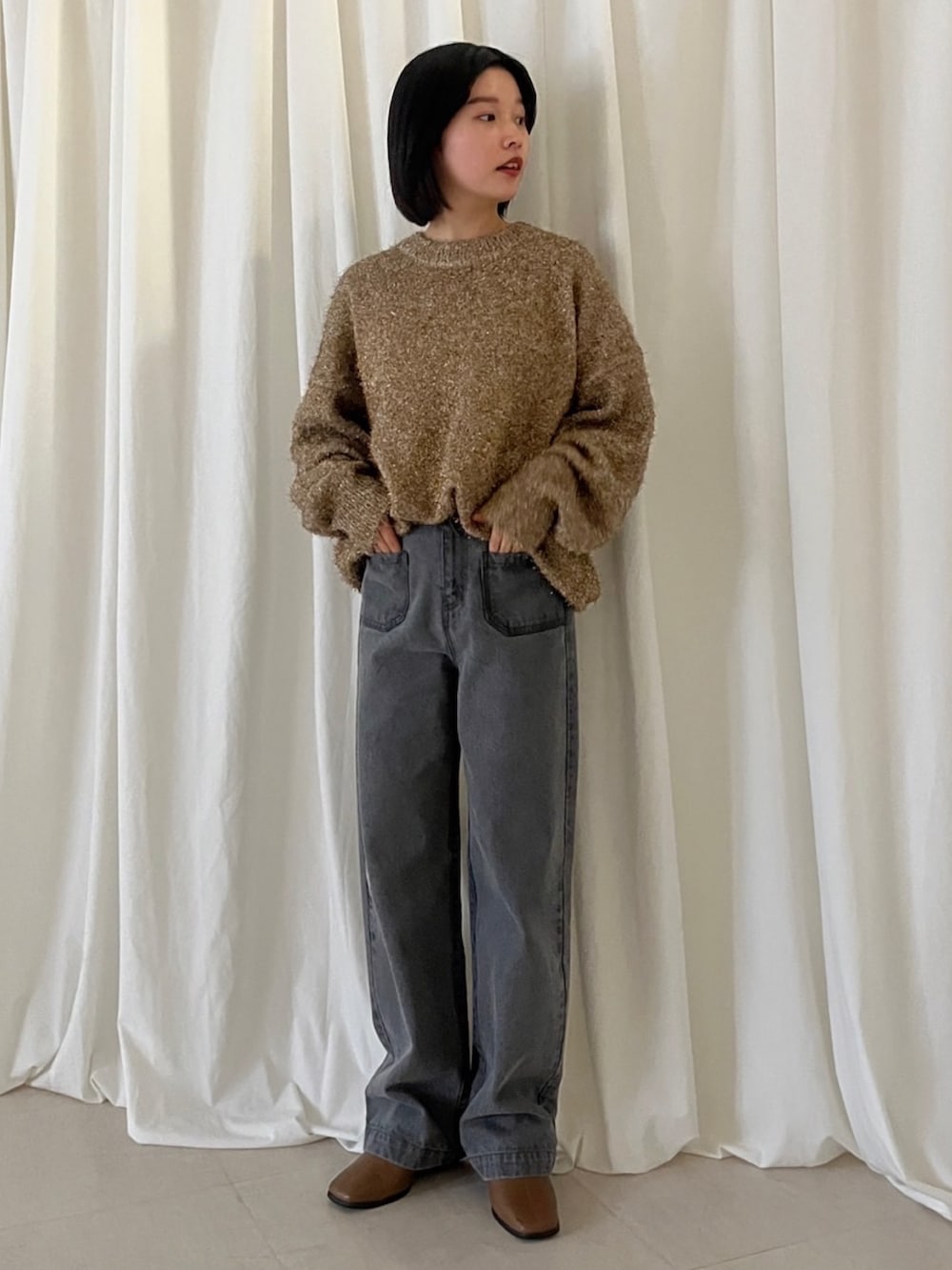 ゴールド系のニット/セーター、グレー系のデニムパンツを着用したレディースの冬コーディネートの2枚目の写真