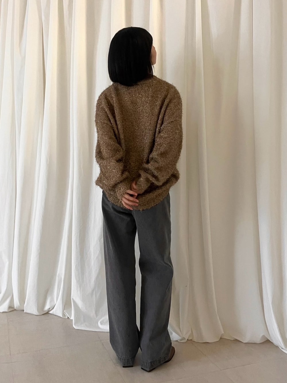 ゴールド系のニット/セーター、グレー系のデニムパンツを着用したレディースの冬コーディネートの3枚目の写真