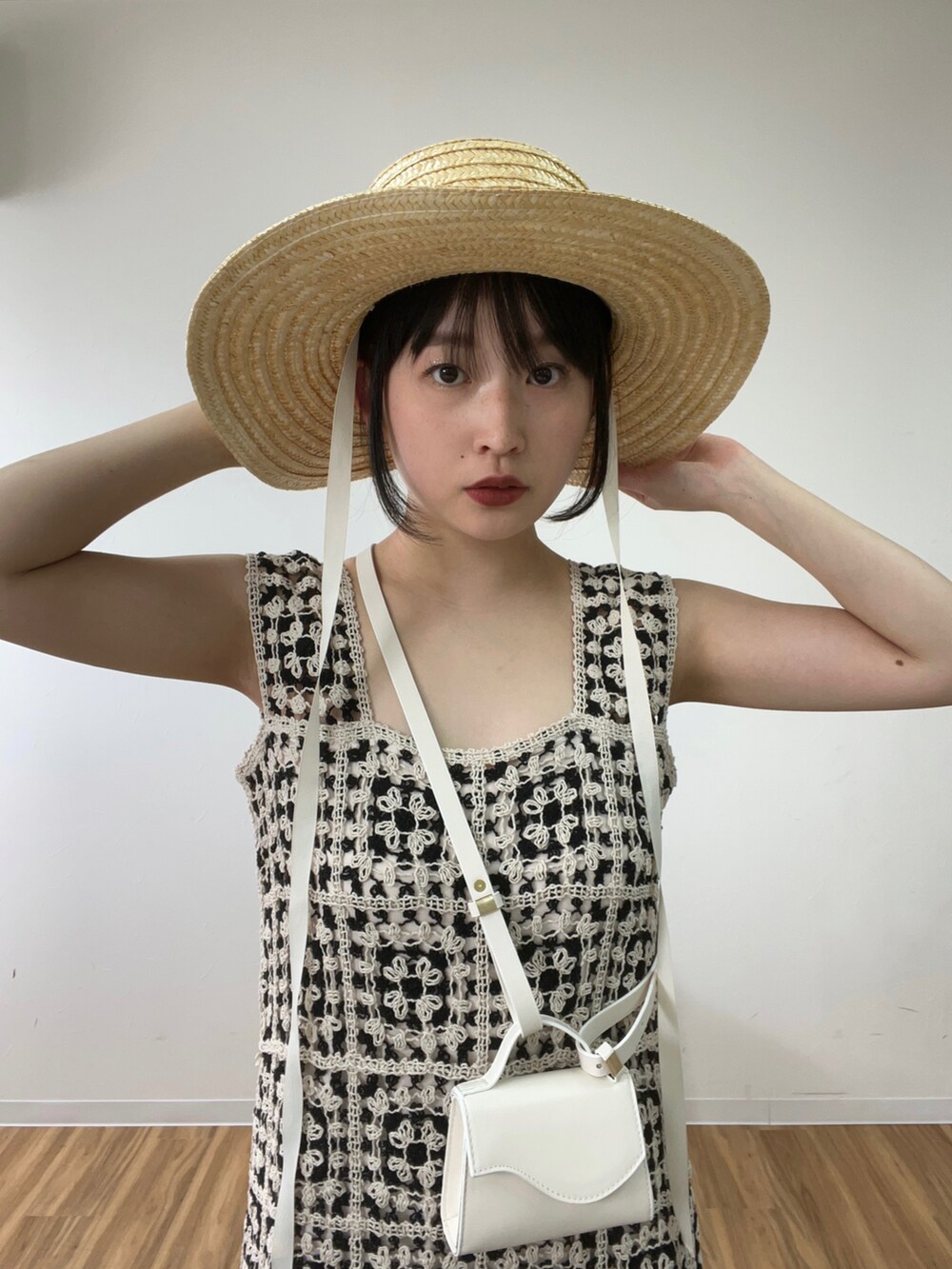 ホワイト系のショルダーバッグ、ブラック系のワンピース、ベージュ系のハットを着用したレディースの春コーディネートの2枚目の写真