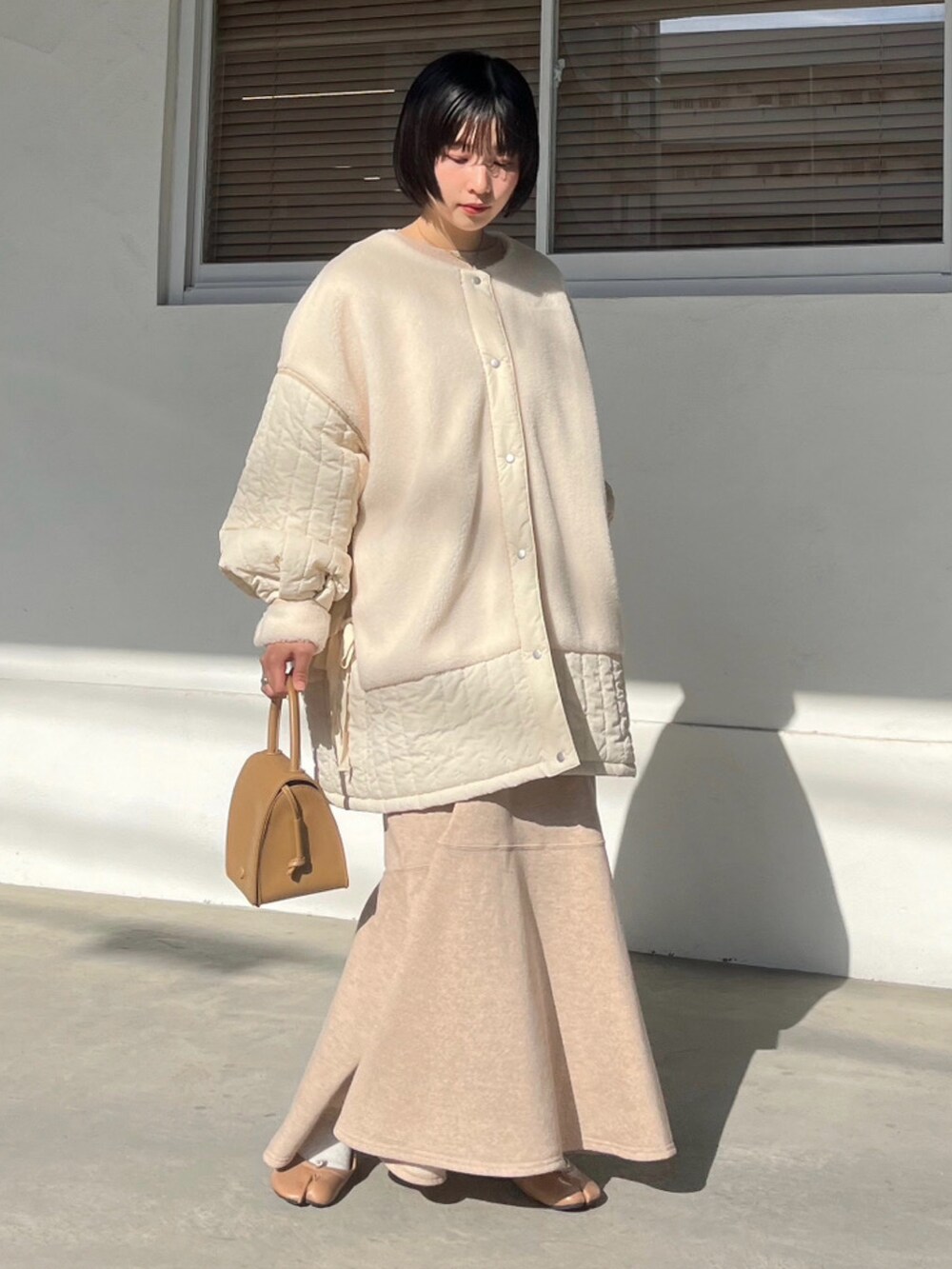 ホワイト系のその他アウター、ベージュ系のワンピースを着用したレディースの冬コーディネートの2枚目の写真