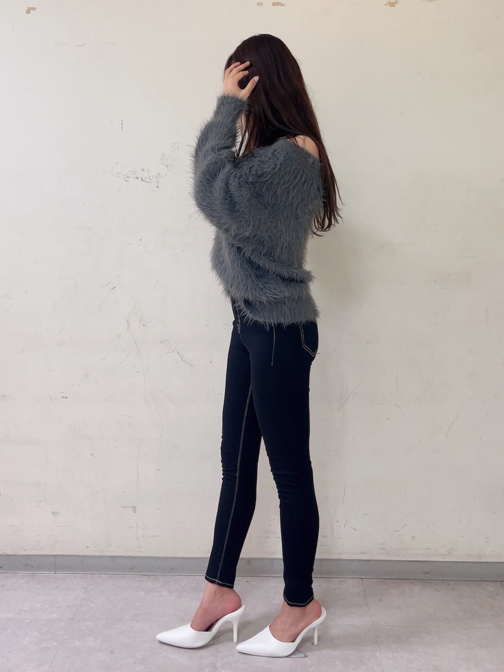 グレー系のニット/セーター、ブラック系のデニムパンツ、ホワイト系のパンプスを着用したレディースの秋コーディネートの3枚目の写真