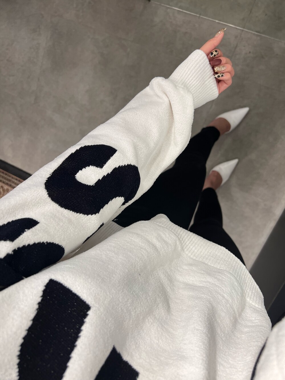 ホワイト系のニット/セーター、ブラック系のデニムパンツ、ホワイト系のパンプスを着用したレディースの秋コーディネートの3枚目の写真