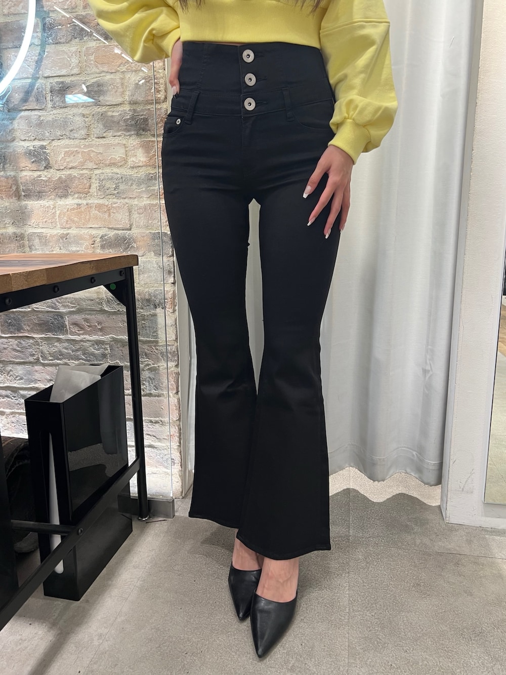 イエロー系のスウェット、ブラック系のデニムパンツ、ブラック系のパンプスを着用したレディースの冬コーディネートの5枚目の写真