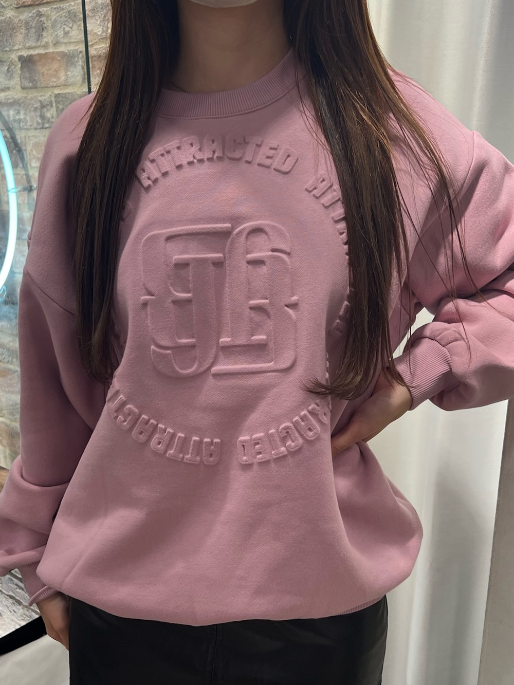 ピンク系のスウェット、ブラック系のスカート、ブラック系のブーツを着用したレディースの冬コーディネートの4枚目の写真