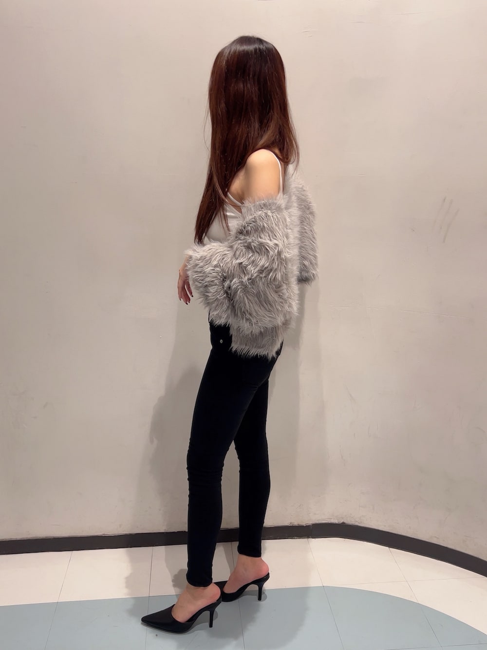 グレー系のカーディガン/ボレロ、ホワイト系のキャミソール、ブラック系のデニムパンツを着用したレディースの秋コーディネートの3枚目の写真